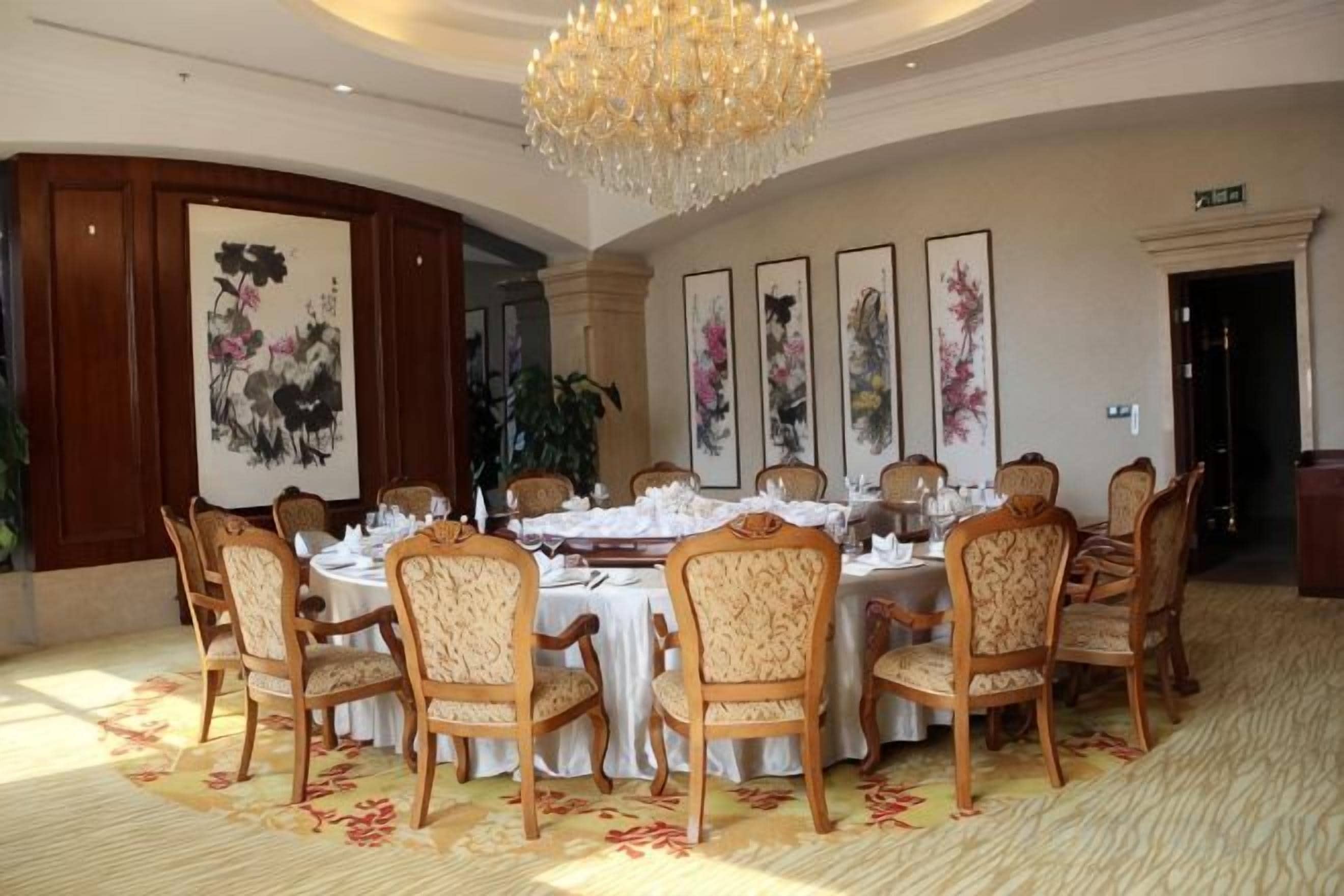 A formal dining room with round tables, chairs, and a chandelier.