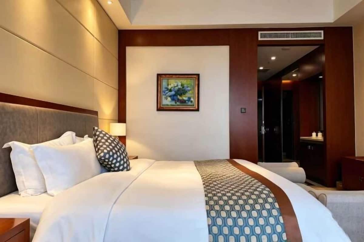 Ein Hotelzimmer mit einem großen Bett, einem Gemälde an der Wand und einem Holzschrank.
