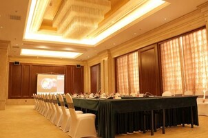 Un salón de conferencias con una larga mesa, sillas y una pantalla para proyector.