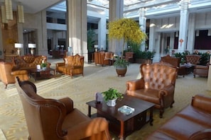 A spacious lobby with leather armchairs, a coffee table, and potted plants.