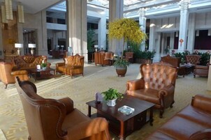 Un hall amplio con sillones de cuero, una mesa de centro y plantas en macetas.