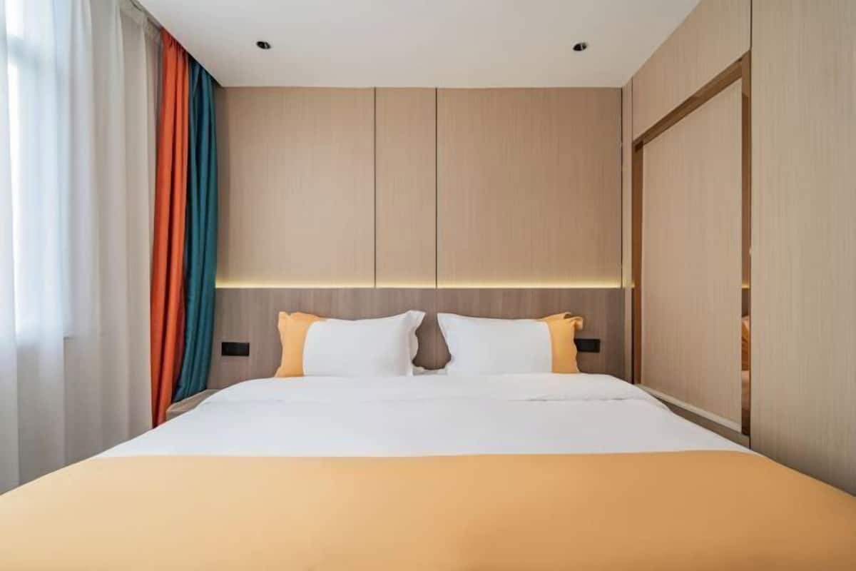 Una habitación de hotel con una cama grande, cabecera de madera y un armario.