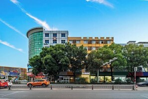 A hotel with a modern design, featuring a curved glass facade and a traditional building with signage.
