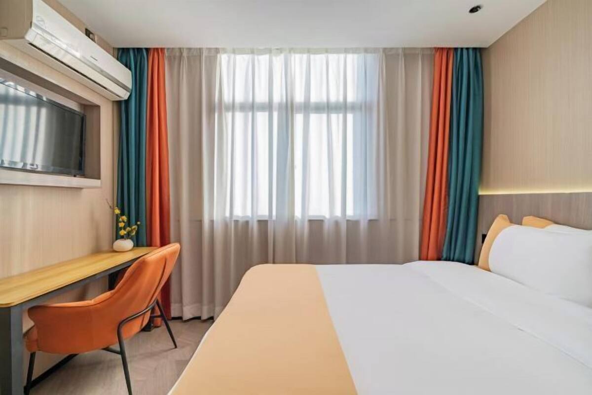 Una habitación de hotel con cama, escritorio y televisión.