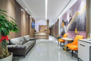 Un lobby moderno de hotel con un sofá, zona de comedor y un mural.