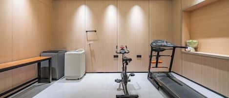 A hotel room with a treadmill, a desk, and a bench.