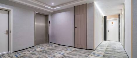 A hotel corridor with a patterned carpet, doors, and a light-colored wall.