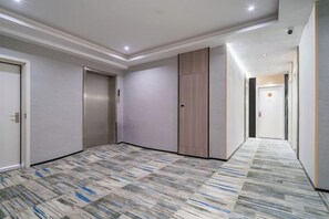 A hotel corridor with a patterned carpet, doors, and a light-colored wall. - Taizhou Jingsha exquisite hotel (Taizhou)