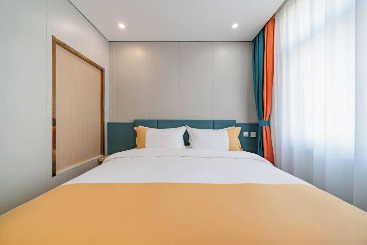 Una habitación de hotel con una cama, una puerta de madera y una ventana con cortinas.