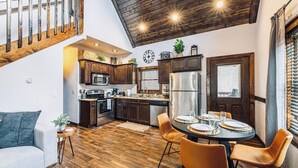 A modern kitchen with dark wooden cabinets, stainless steel appliances, and a dining area with a round table and chairs. - 2 King BRs-HotTub,Wifi,Pets,Mins to DT Sevierville (Sevierville)