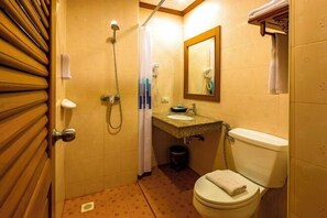 Een kleine badkamer met douche, toilet, wastafel en spiegel.