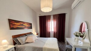 A bedroom with a bed, bedside table, dresser, and a mirror.