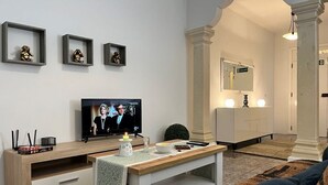 A modern living room with a TV, framed pictures, a small table with candles, and a sofa.