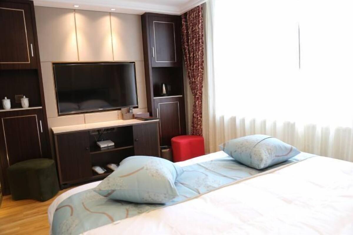A hotel room with a bed, a TV, a desk, and a wardrobe.