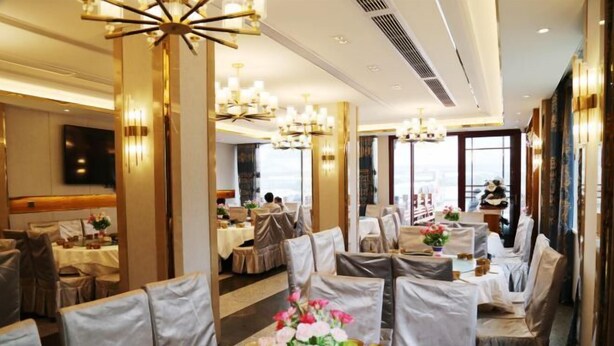 Une salle à manger bien éclairée, avec des tables rondes, des chaises et des lustres.