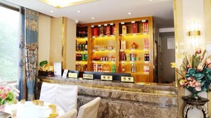 Un espace d’accueil d’hôtel avec un comptoir en marbre, une variété de boissons en bouteille et une composition florale.