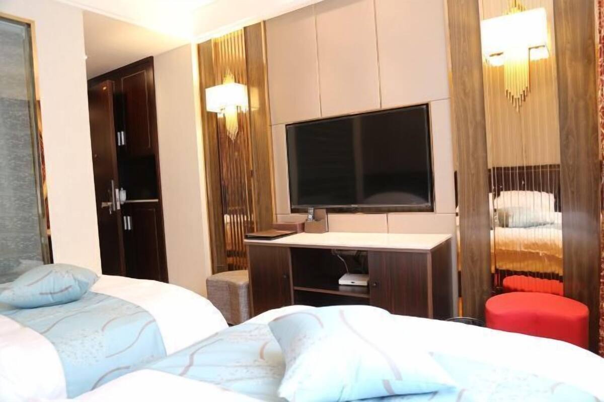 A hotel room with a bed, a TV, a desk, and a wardrobe.