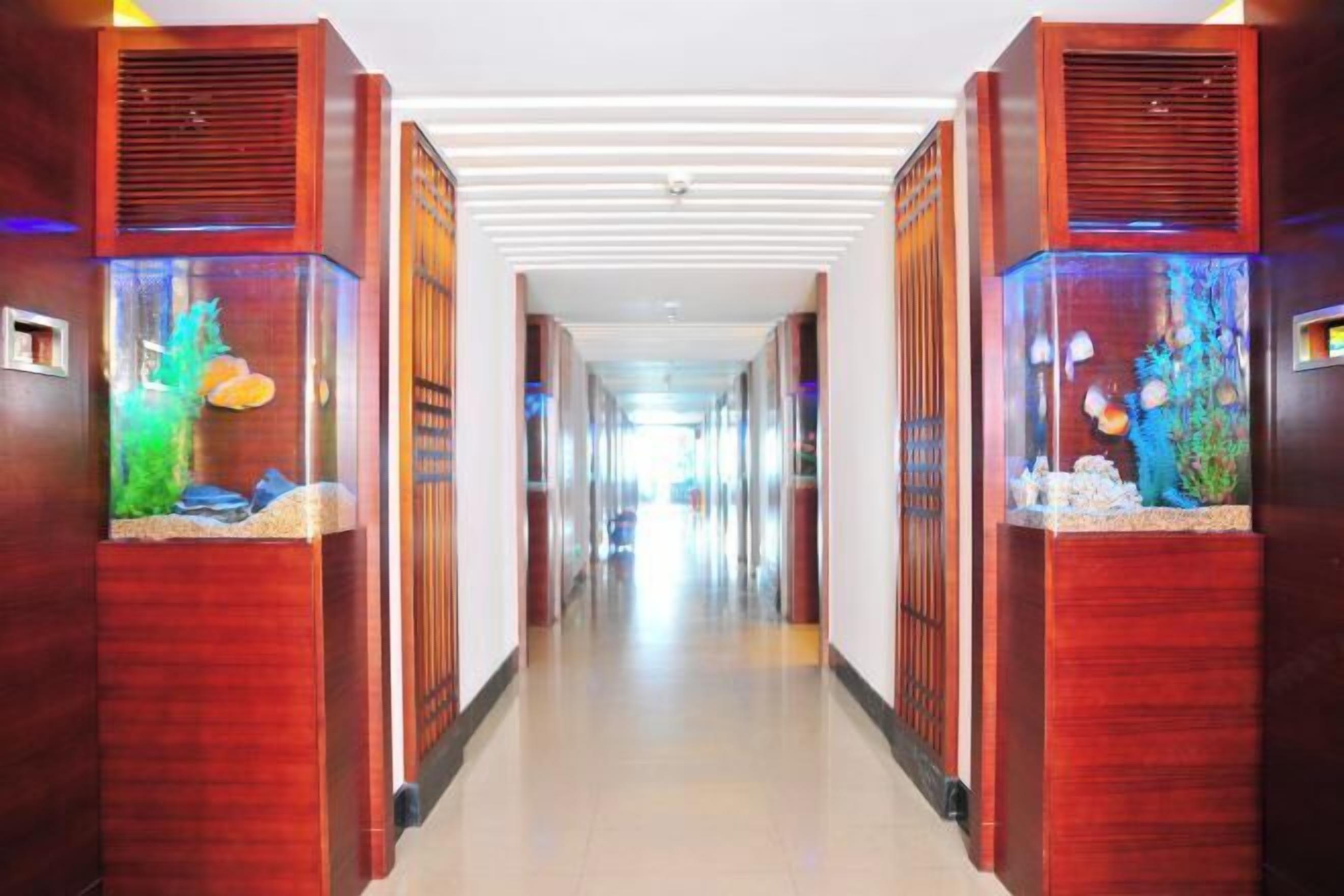 A hotel corridor with wooden paneling and aquarium features on either side.