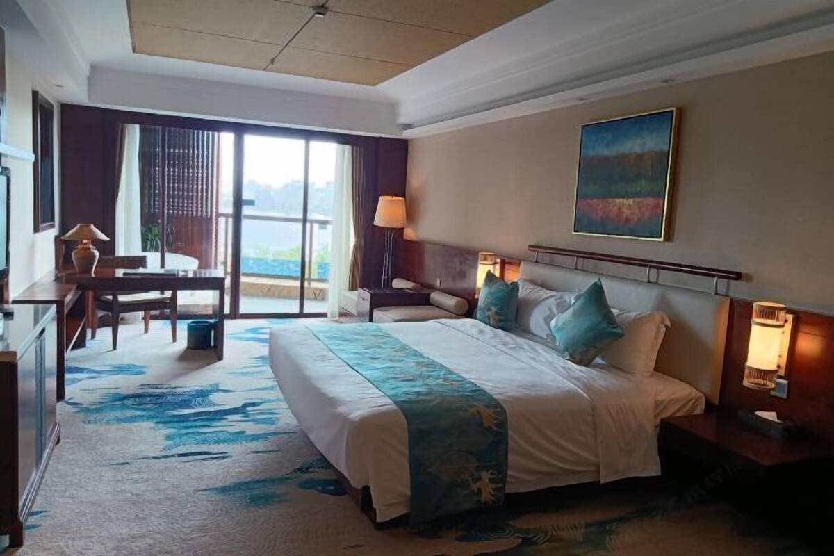 A hotel room with a large bed, a desk, and a view of the outdoors.