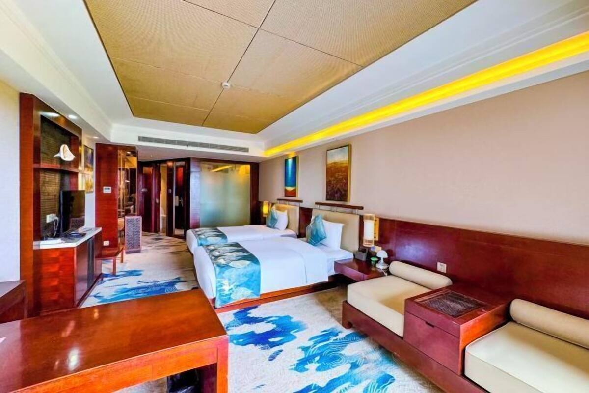 A hotel room with a bed, a sofa, a desk, and a mirror.