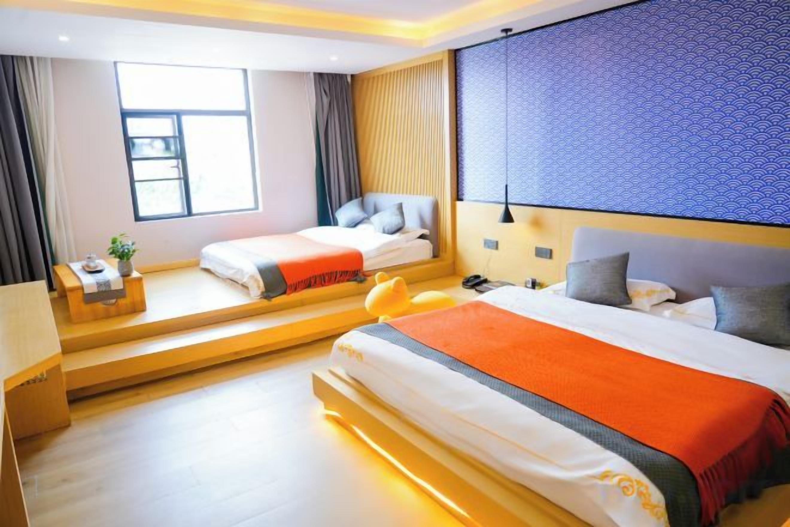 Quarto de hotel com duas camas, uma janela, uma escrivaninha e uma mesa de cabeceira.