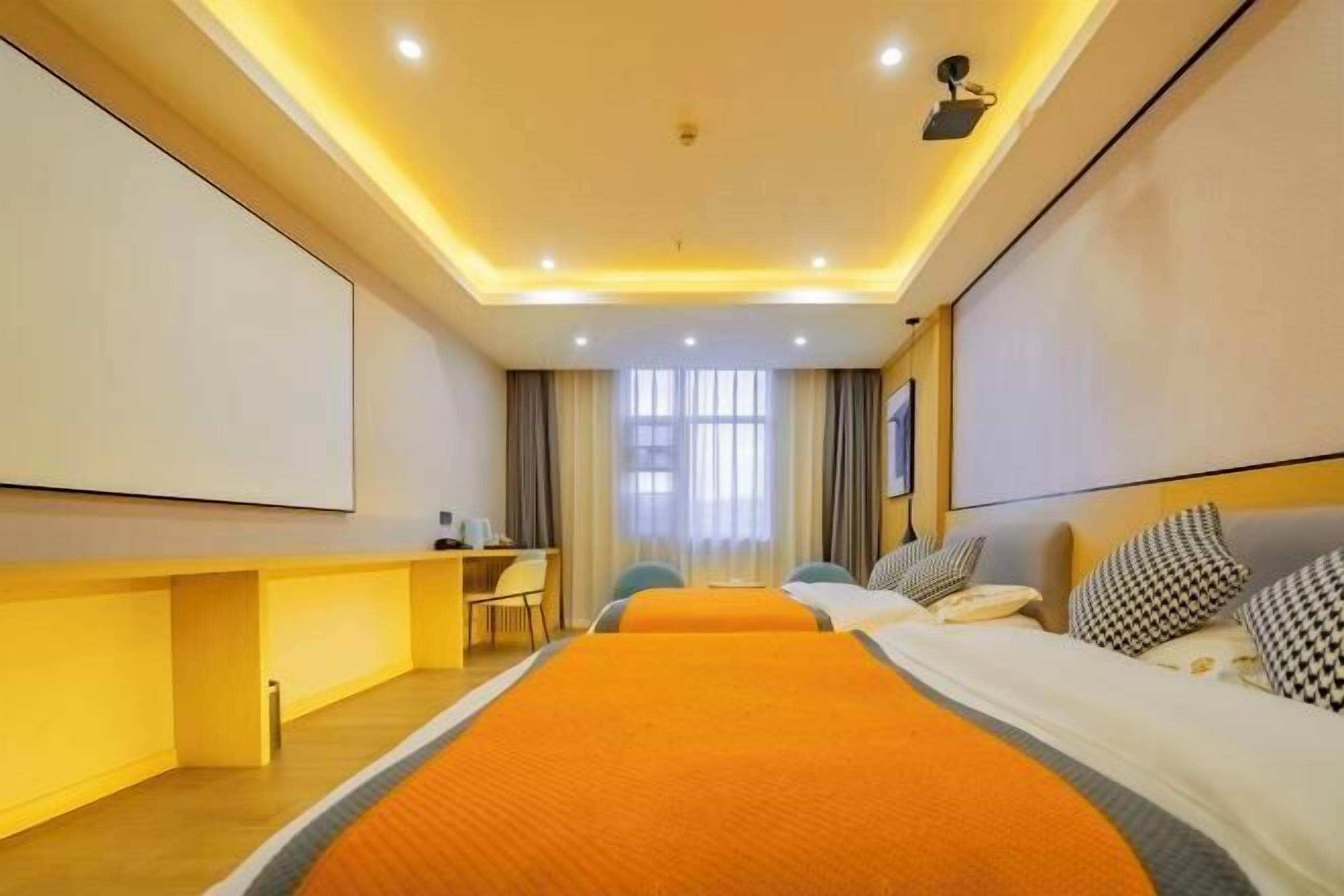 Une chambre d’hôtel avec deux lits, un bureau, une chaise et une grande fenêtre.