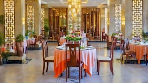 A restaurant with round tables, orange tablecloths, and a chandelier. - Jianlang Holiday Hot Spring Hotel (Shilin)