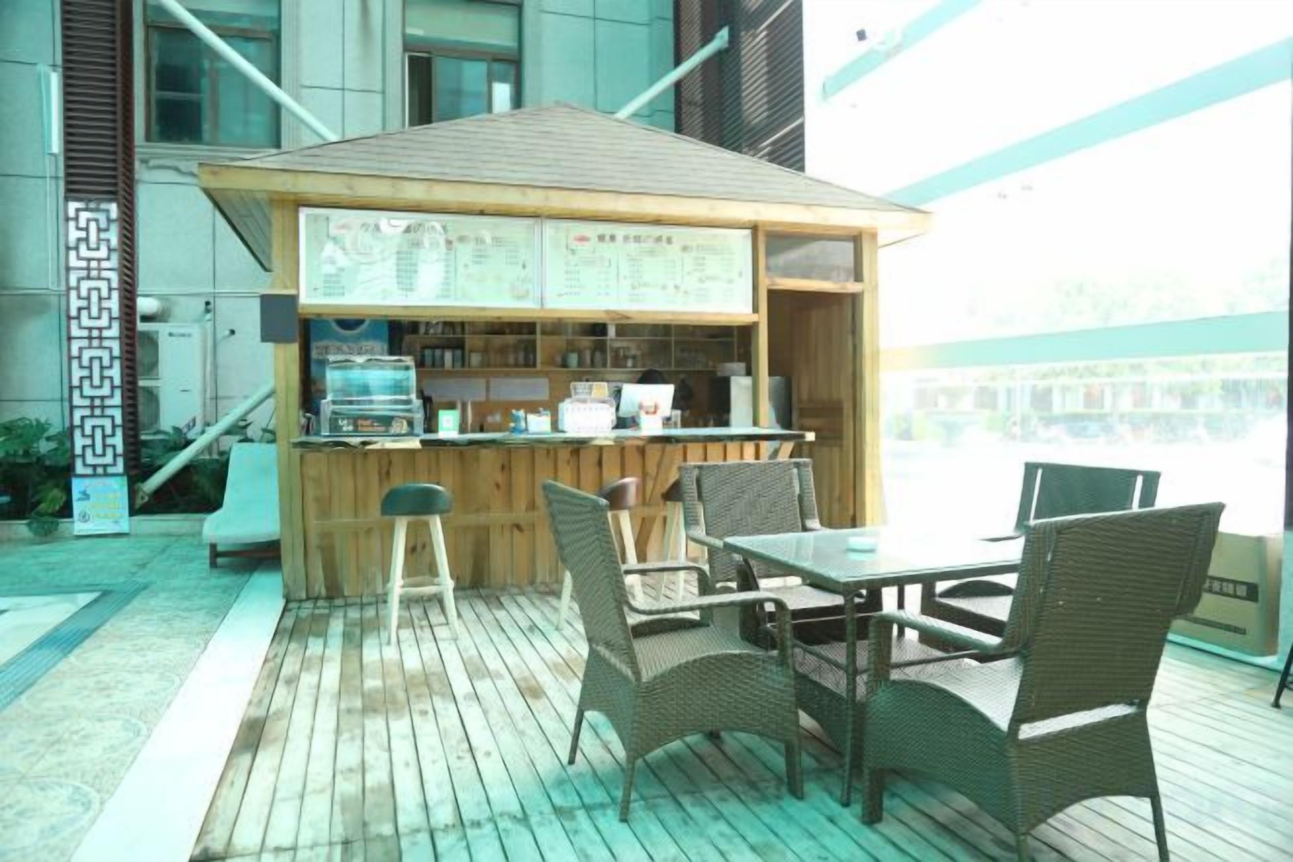 An outdoor bar area with a wooden counter, seating, and a view of the city.