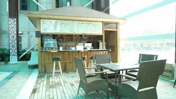 An outdoor bar area with a wooden counter, seating, and a view of the city.