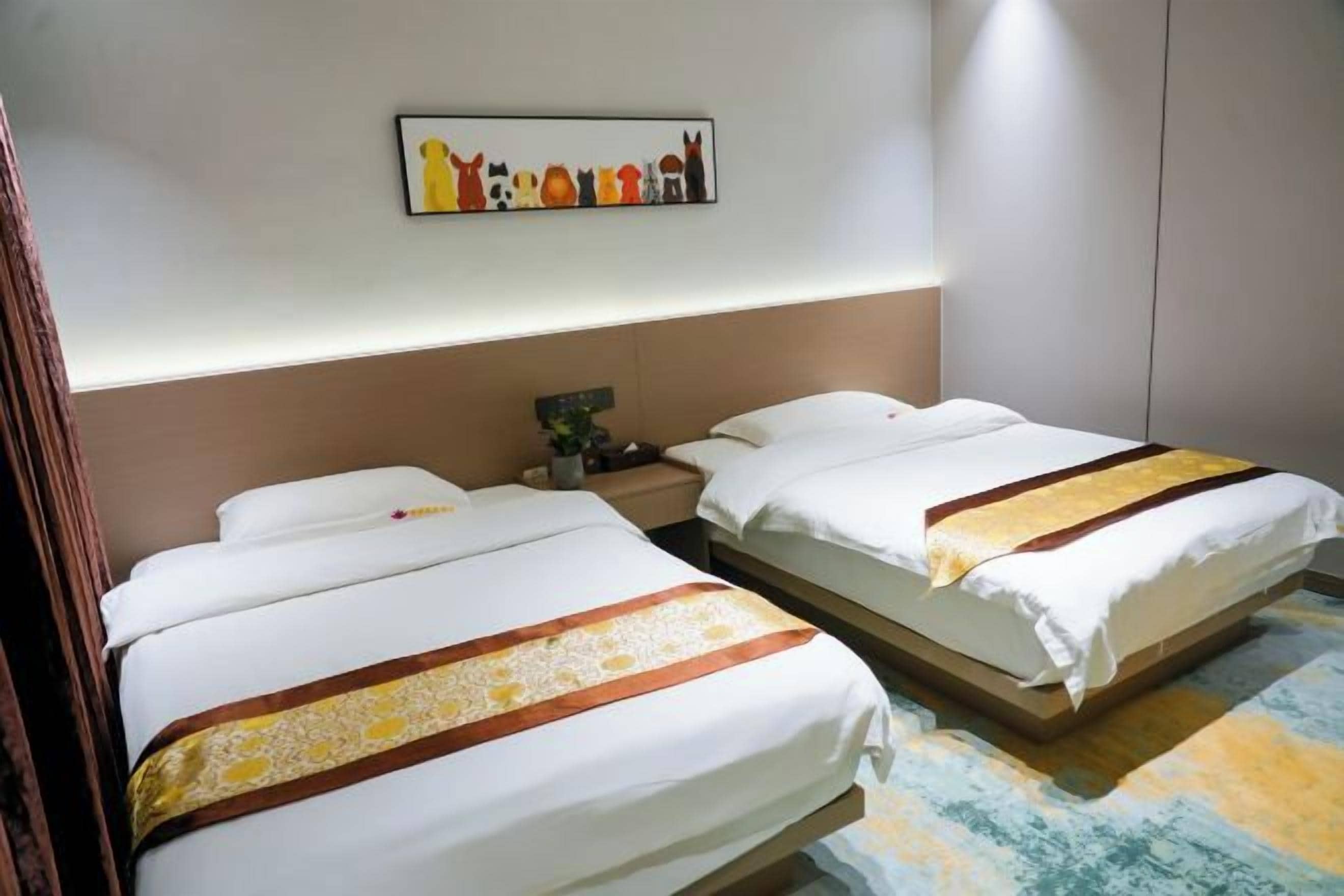 A hotel room with two beds, a nightstand, a wall-mounted artwork, and a patterned carpet.