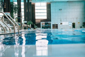 An indoor swimming pool with clear water, surrounded by a tiled wall and a staircase leading to an upper level. - Jianlang Holiday Hot Spring Hotel (Shilin)