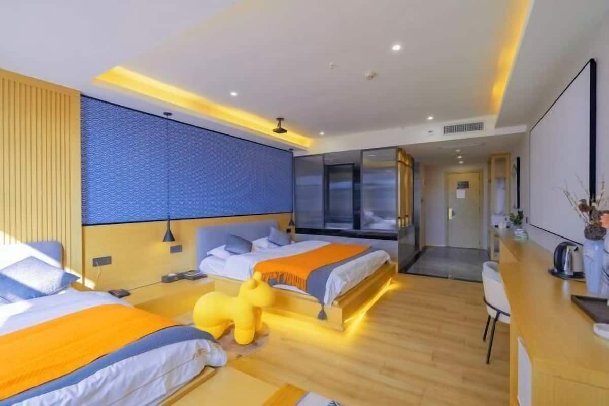 A modern hotel room with two beds, a desk, and a large window.