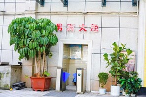 A building entrance with a sign in red characters, a potted plant, and a door. - Jianlang Holiday Hot Spring Hotel (Shilin)