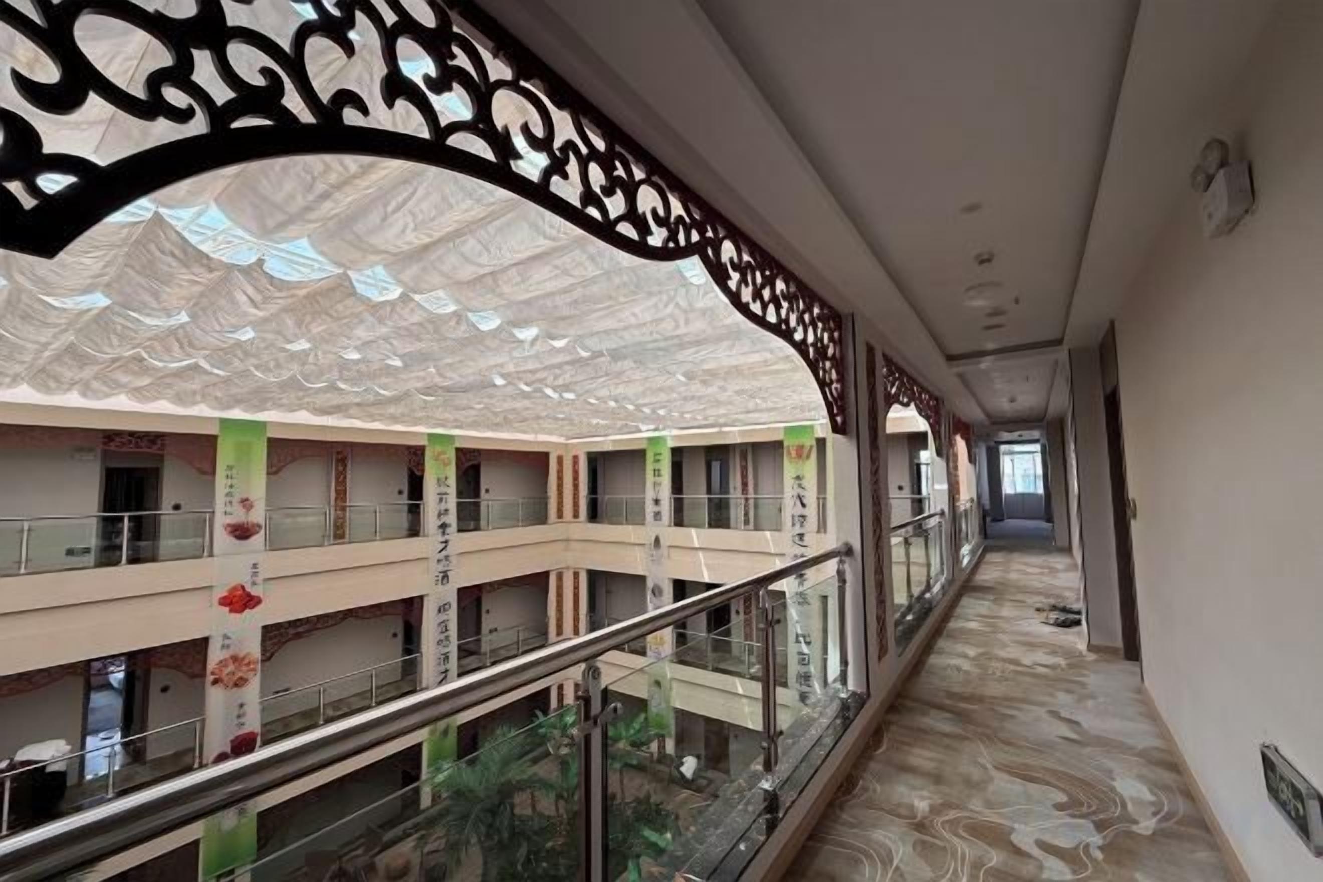 A corridor with a glass railing, decorative ceiling, and multiple floors with balconies.