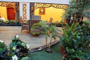 A wooden deck with outdoor furniture, surrounded by potted plants and a well-maintained lawn. - Jianlang Holiday Hot Spring Hotel (Shilin)