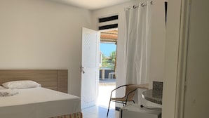 Habitación de hotel con cama, una mesita con silla, bañera y vistas al exterior.