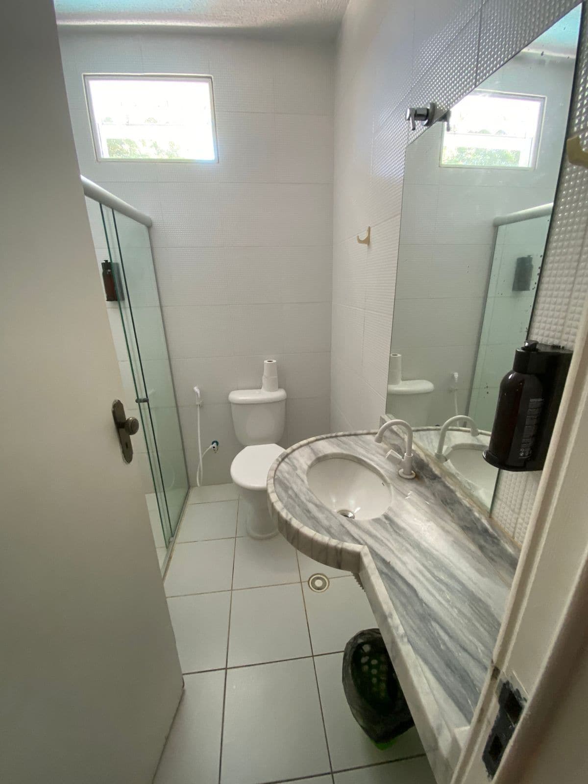 A bathroom with a toilet, sink, and glass shower enclosure.