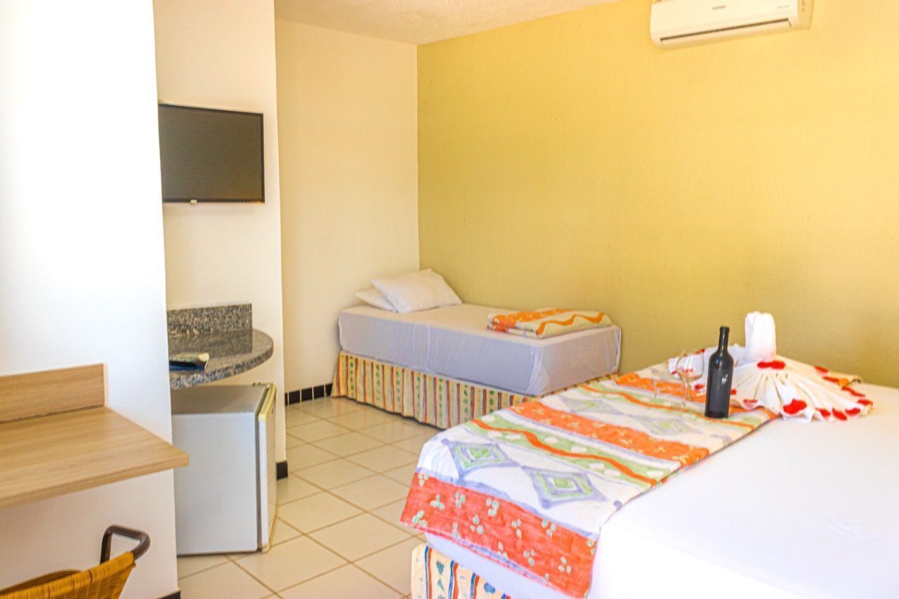 Une chambre d’hôtel avec deux lits, un petit bureau, une télévision et un appareil de climatisation.