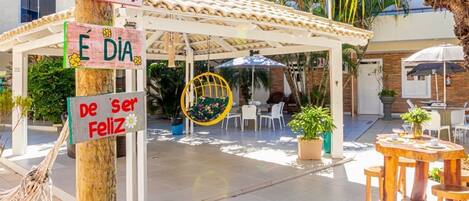 An outdoor patio area with a covered seating area, tables, and chairs.