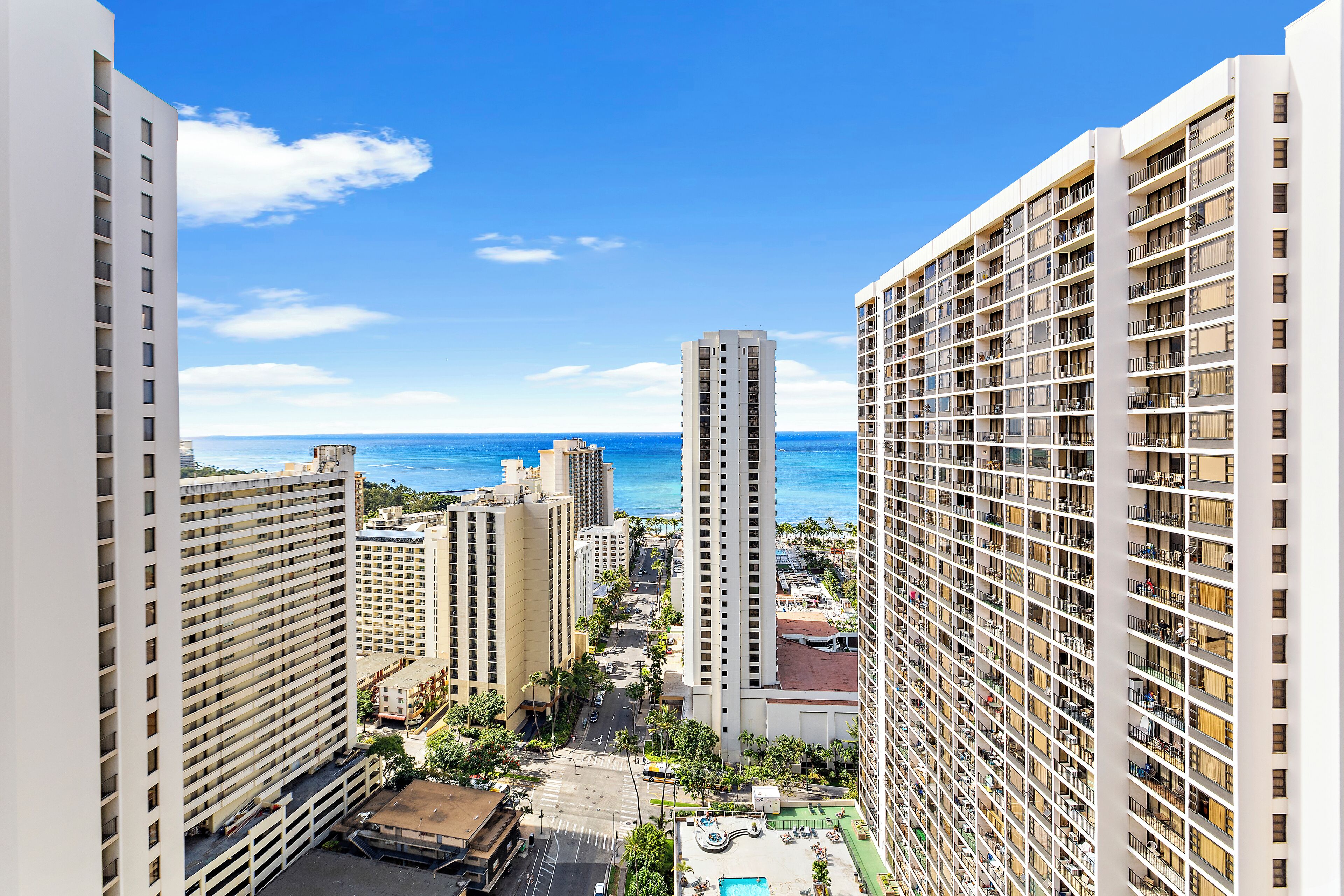 A high-rise hotel with multiple floors, a central courtyard, and a view of the ocean.