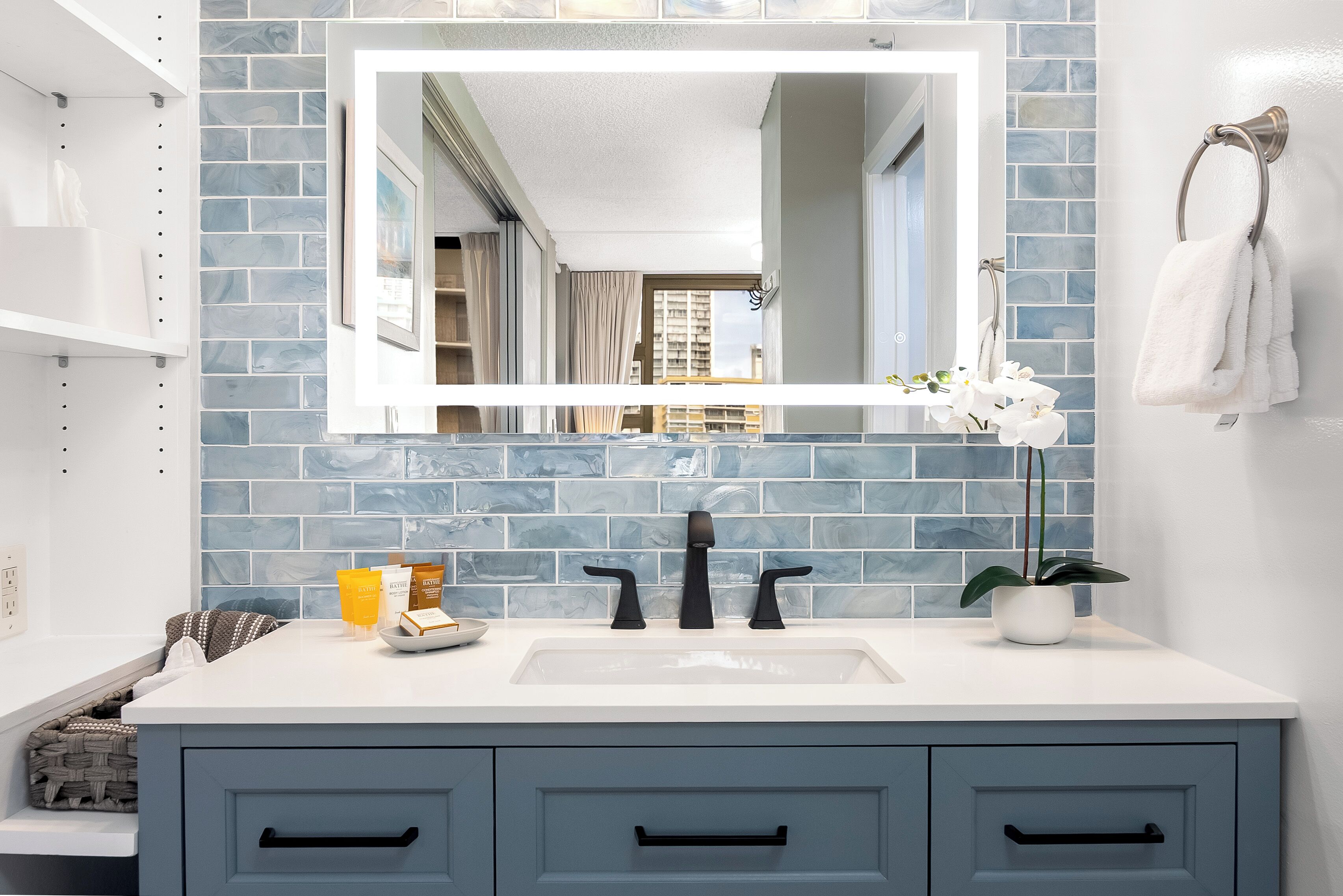 Un baño con lavamanos blanco, azulejos azules, un espejo y un perchero para toallas.