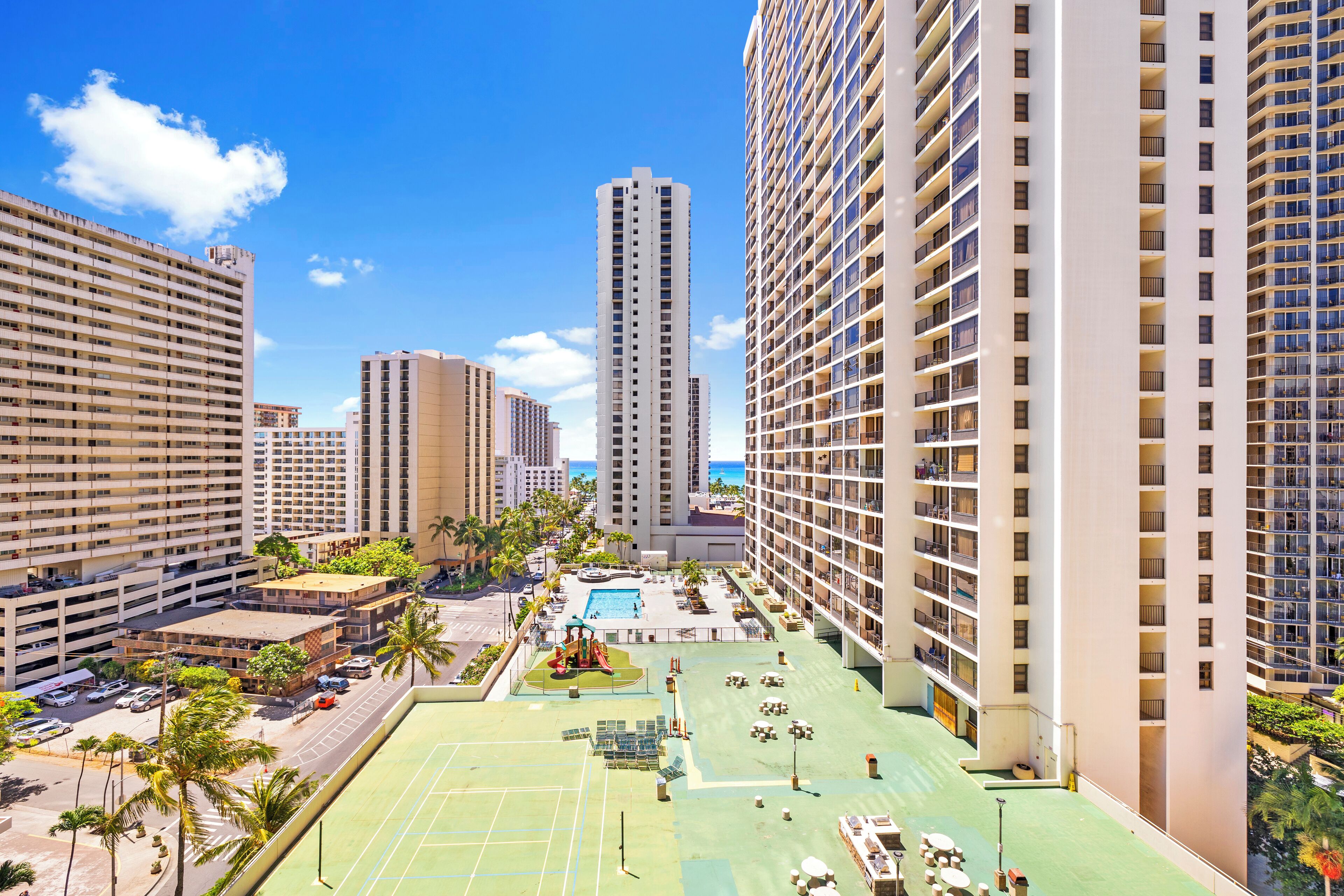 A high-rise hotel with multiple floors, a rooftop pool, and surrounding greenery.