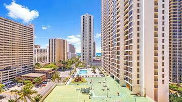 A high-rise hotel with multiple floors, a rooftop pool, and surrounding greenery.