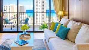 A living room with a sofa, a coffee table, and a view of the ocean through large windows.