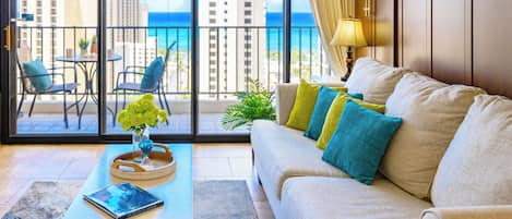 A living room with a sofa, a coffee table, and a view of the ocean through large windows.