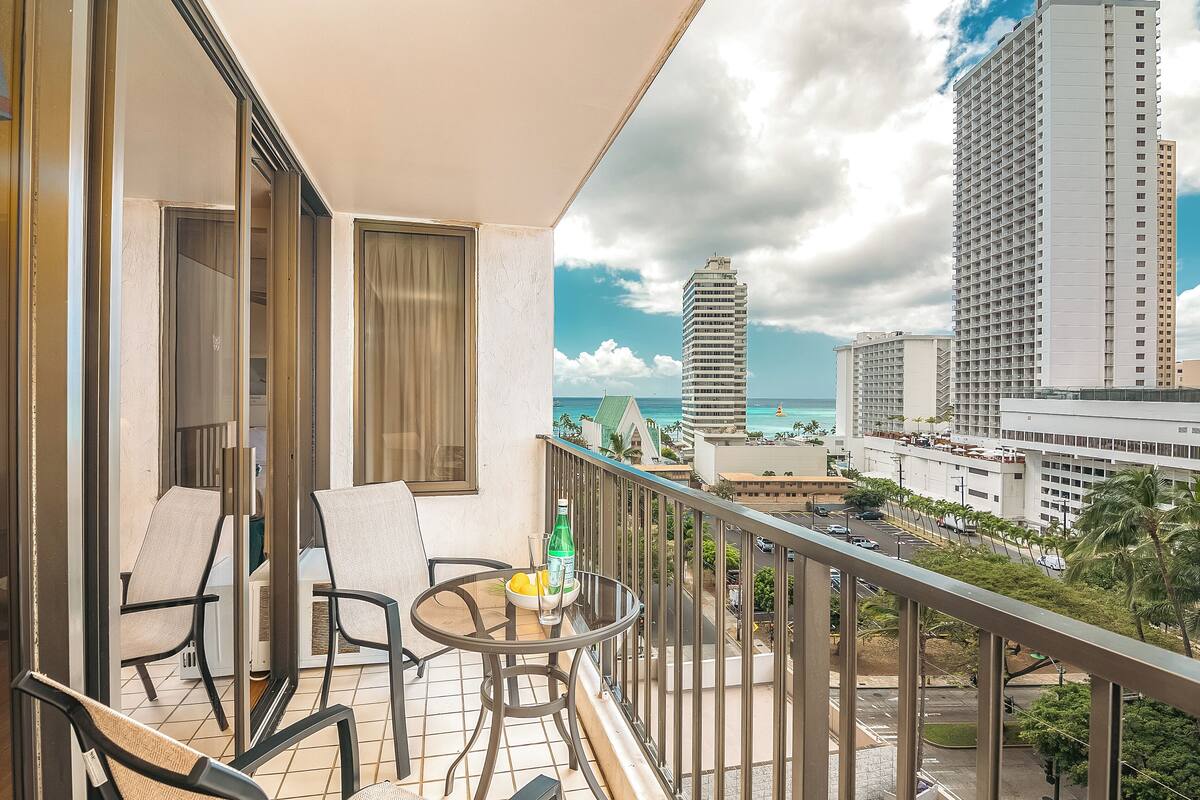 Ein Balkon mit Tisch und Stühlen, mit Blick auf Stadt und Meer.