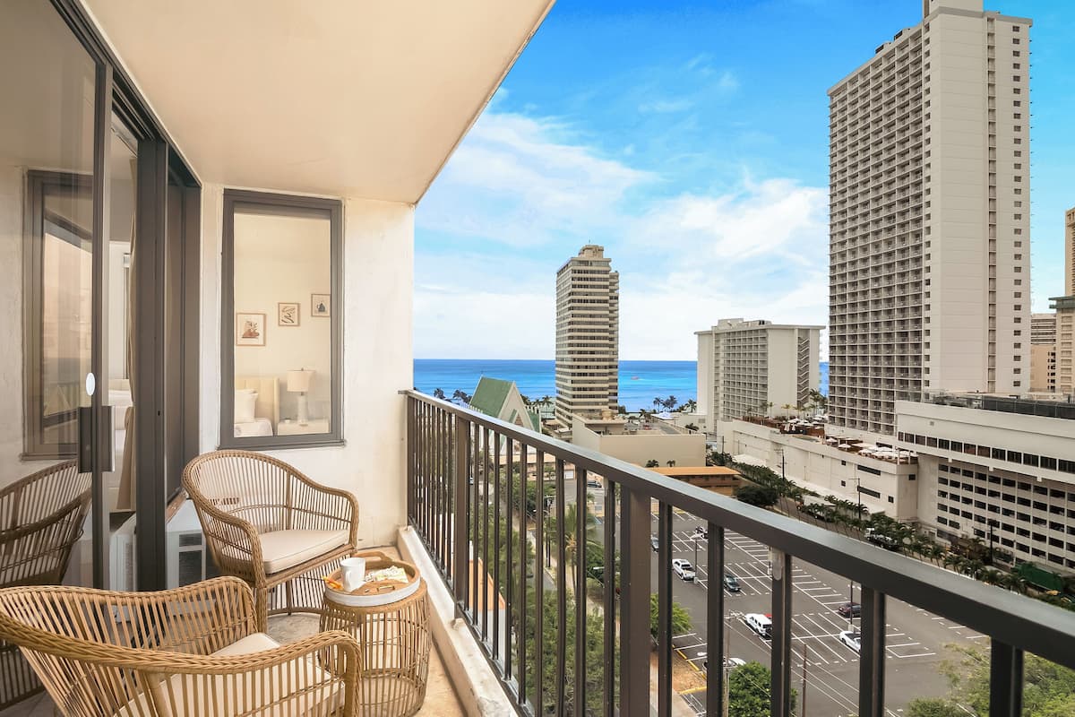 Ein Balkon mit Korbmöbeln und Blick auf die Stadt und das Meer.