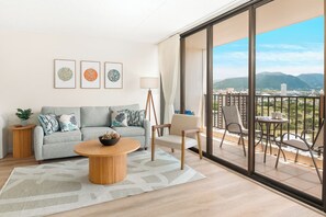 Relax in this stylish living room with a sofa, coffee table, and side table, featuring a balcony with city and mountain views.
