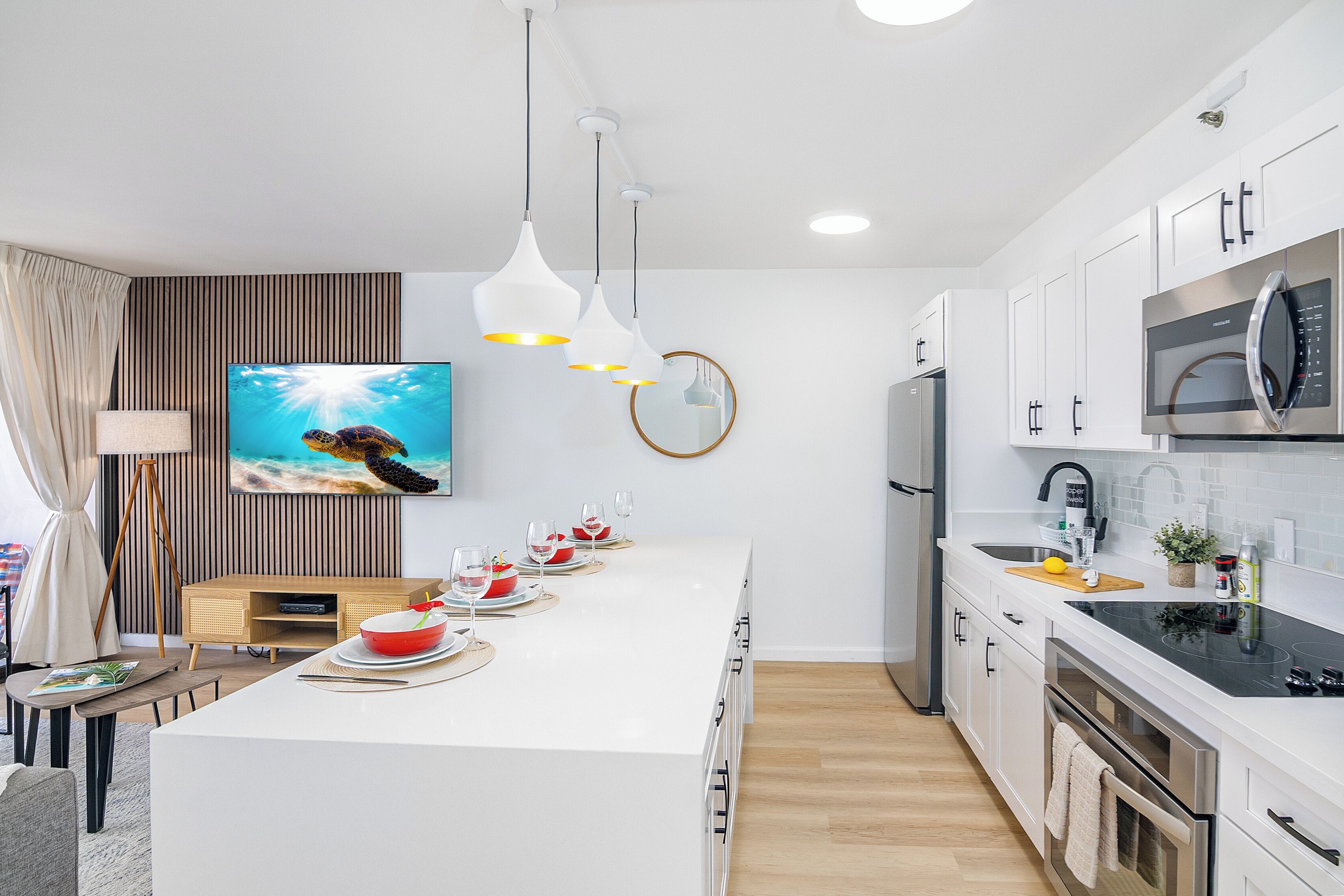 Een moderne keuken met een centraal eiland, witte kasten en roestvrijstalen apparatuur.
