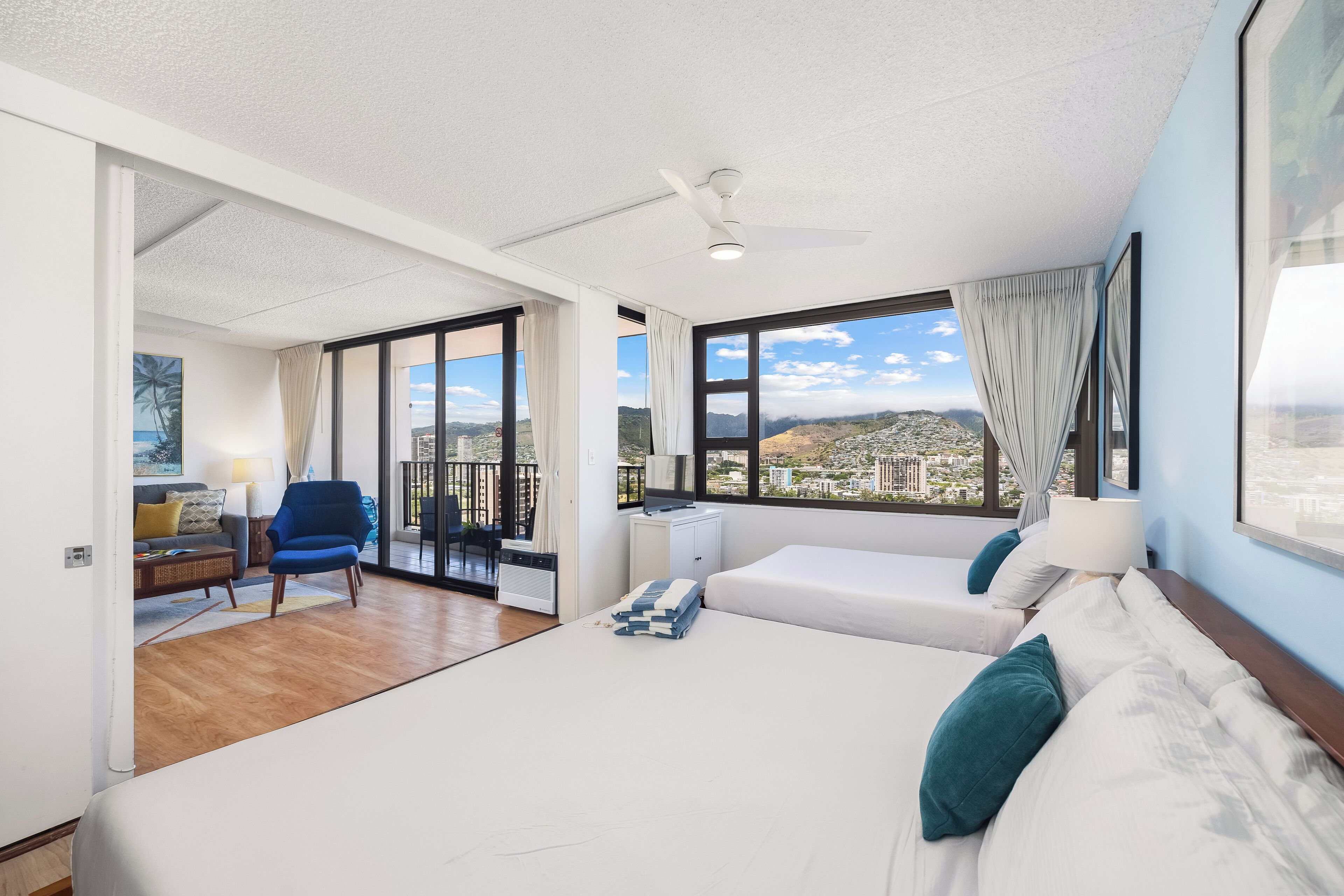 A modern hotel room with a large bed, a desk, a chair, and a balcony with a city view.
